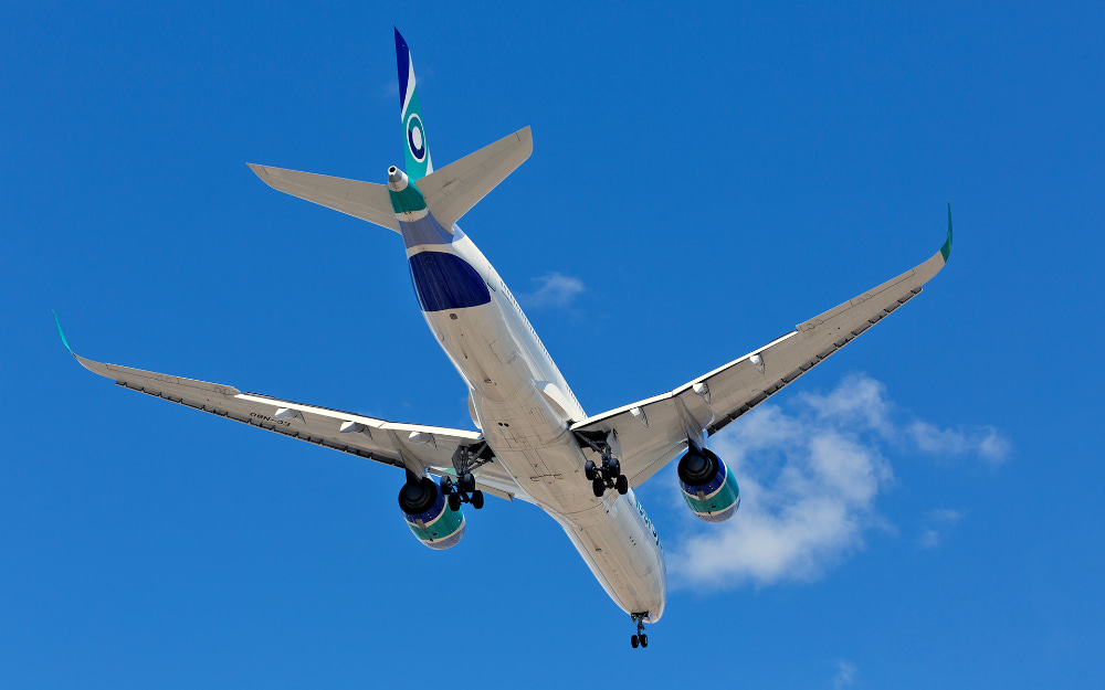 Un A350 a punto de aterrizar visto desde abajo a la derecha y detrás con el cielo azul de fondo