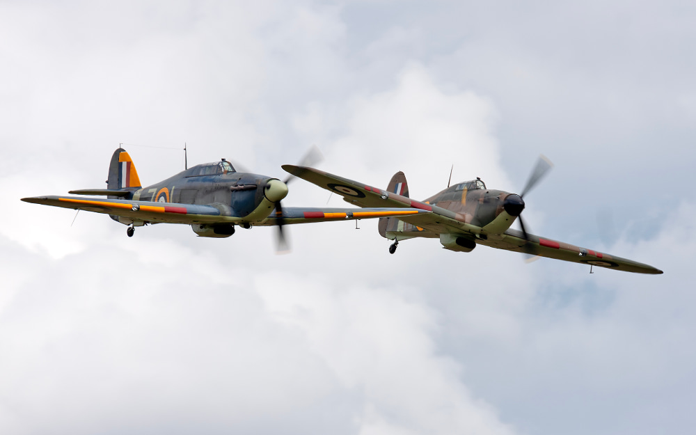 Los dos aviones volando lado a lado frente a un cielo nublado