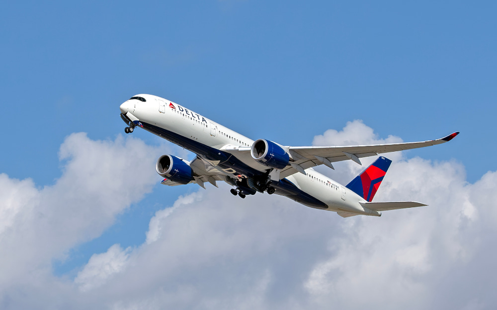 Una Airbus A350 recogiendo el tren de aterrizaje con un cielo azul parcialmente nublado de fondo